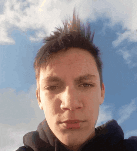 a young man taking a picture of himself with a blue sky in the background