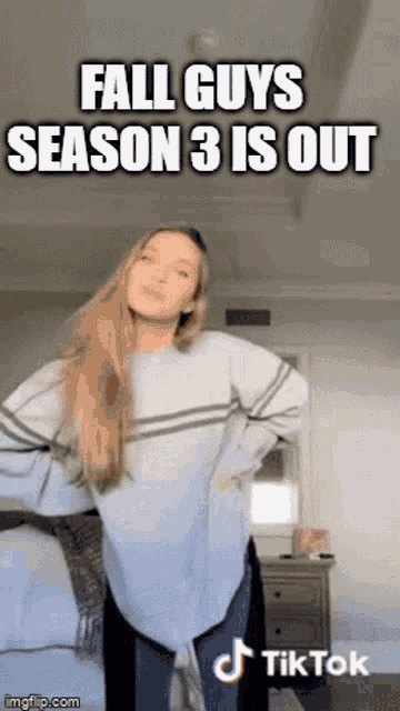 a woman in a blue sweater is dancing in a room with the caption fall guys season 3 is out .