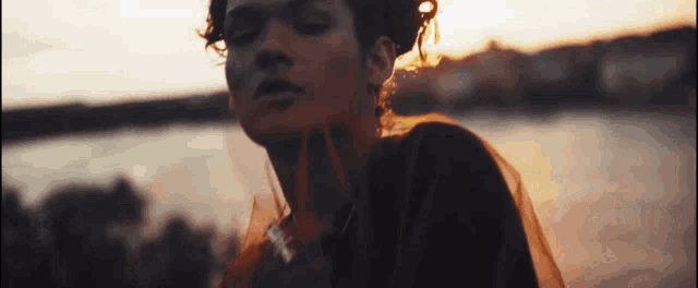 a woman is standing in front of a body of water .