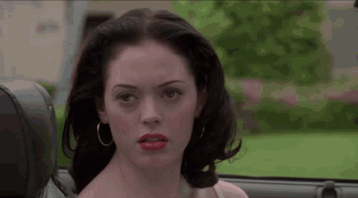 a woman with red lipstick and hoop earrings is sitting in a car