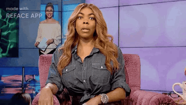 a woman in a denim shirt is sitting in a pink chair and making a face .