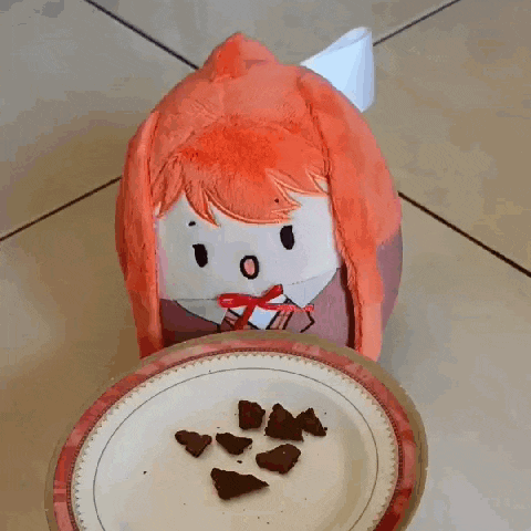 a stuffed animal is sitting on the floor looking at a plate of food .
