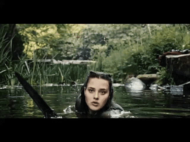 a woman is swimming in a body of water with a sword in her hand
