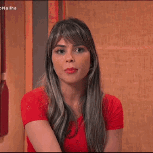 a woman is wearing a red shirt and a ring on her finger .