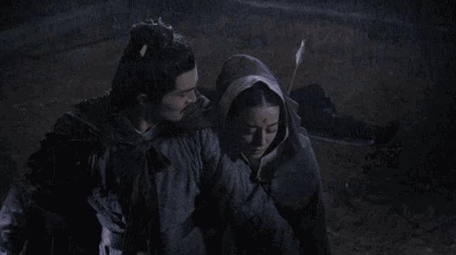 a man is holding a woman who is laying on the ground in the rain .