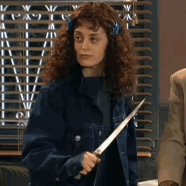 a woman in a denim jacket is holding a knife