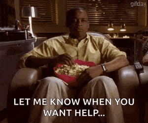 a man is sitting in a chair eating popcorn and saying `` let me know when you want help . ''