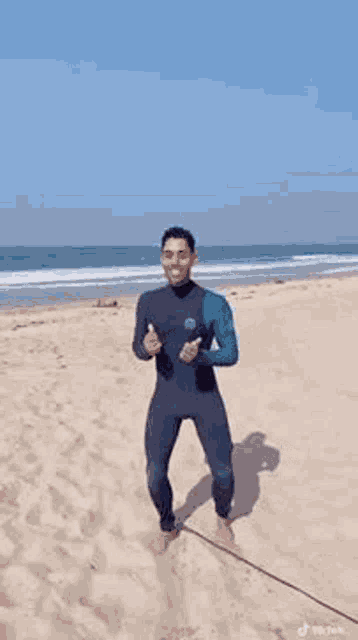 a man in a wetsuit is dancing on a beach .