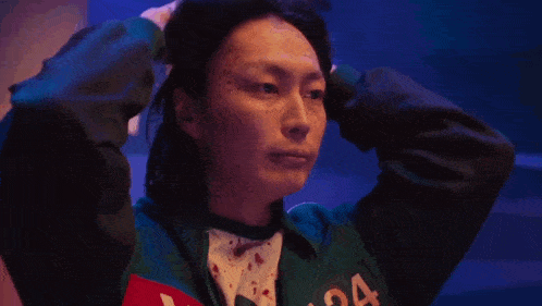 a woman in a green jacket is holding her head in pain .
