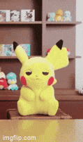 a pikachu stuffed animal is sitting on a table in front of shelves .