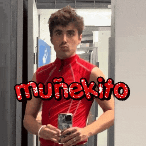a man in a red vest is taking a picture of himself in front of a mirror with muneko written on it