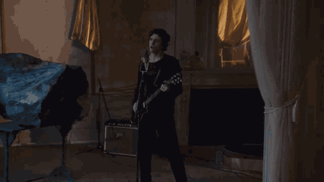 a man is singing into a microphone while holding a guitar