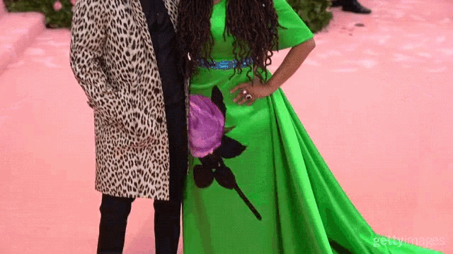 a woman in a green dress is standing next to a man in a leopard print jacket