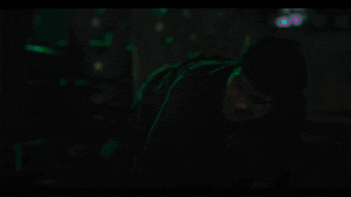 a person dancing in a dark room with a neon sign that says ' a ' on it