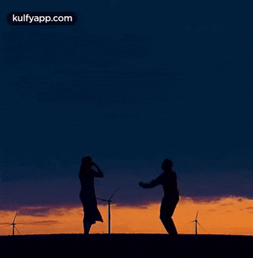 a man is jumping in the air while a woman takes a picture of him .