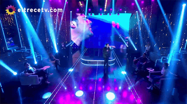 a man singing on a stage in front of a large screen that says " entrectv.com "