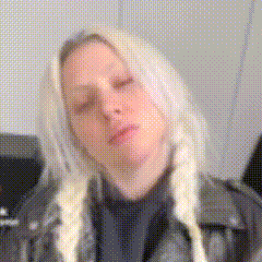 a woman with blonde hair and pigtails is wearing a black leather jacket and a black shirt .