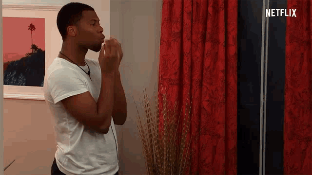 a man blowing a kiss in front of a red curtain with netflix written on the bottom