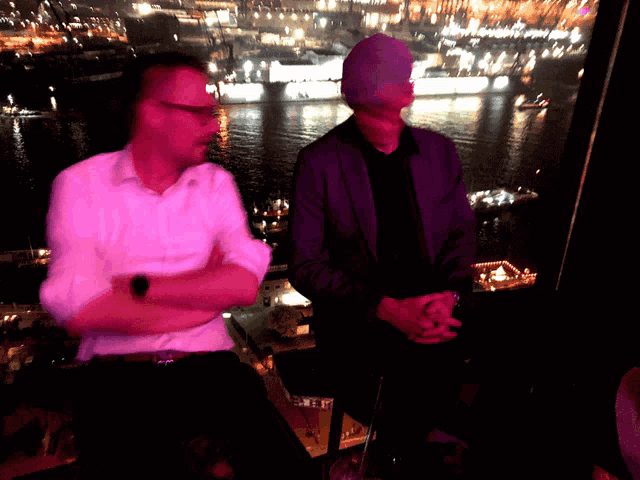 a man in a purple jacket is standing next to a man in a white shirt