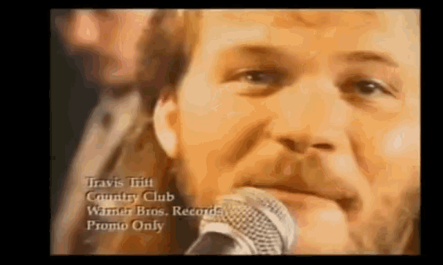 a close up of a man singing into a microphone with the words travis tritt country club warner bros. records promo only