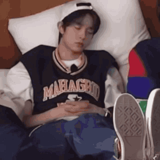 a young man is laying on a bed with his feet up and looking at his phone .