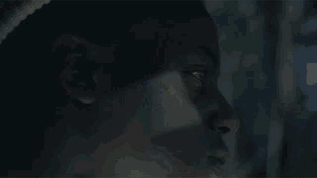 a close up of a person 's face in the dark looking at the camera .