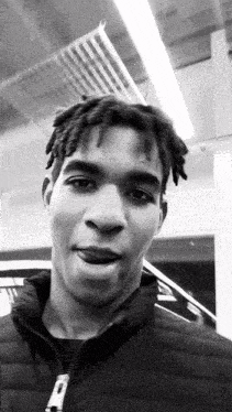 a black and white photo of a man wearing a black jacket with the letter p on it