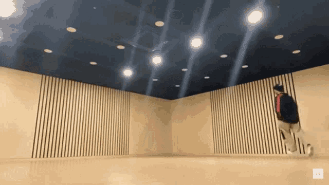 a person is jumping in a room with a blue ceiling and wood paneling
