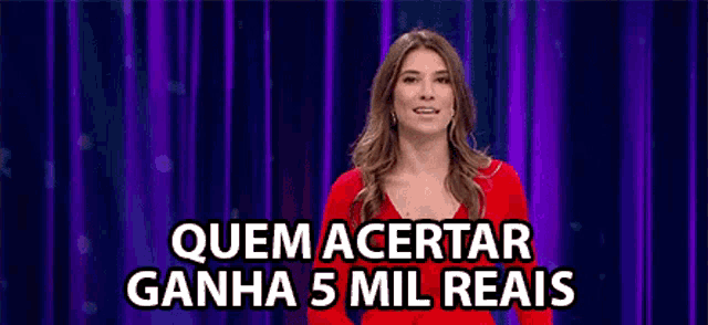 a woman in a red dress is standing in front of a purple curtain and says quem acertar ganha 5 mil reais