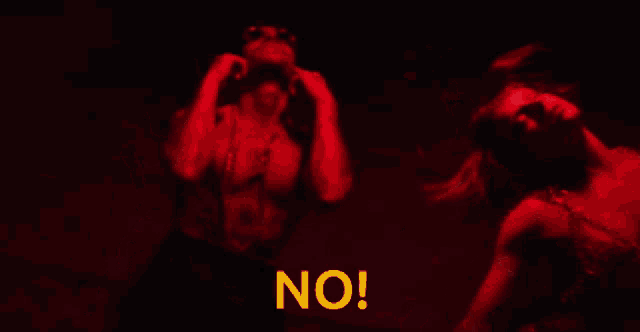 a man and a woman are dancing in a dark room with the word no in yellow letters