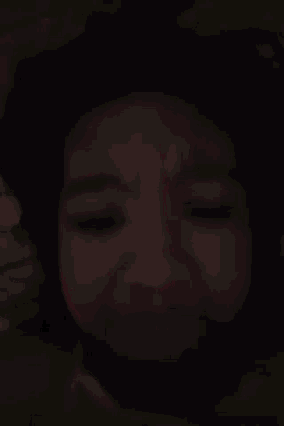 a close up of a person 's face with their eyes closed in the dark