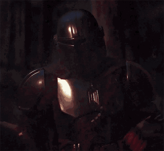 a close up of a person in armor with a red light behind them