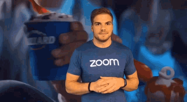 a man wearing a zoom t-shirt is holding a dairy queen cup