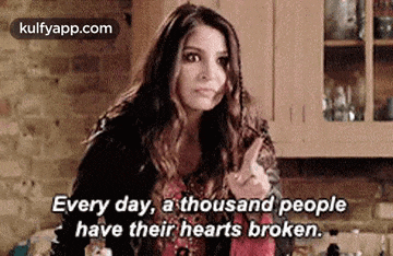 a woman is sitting in a kitchen with her finger up and a quote .