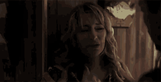 a woman is being held by a man in a dark room .