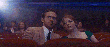 a man and woman are sitting next to each other in a theater .