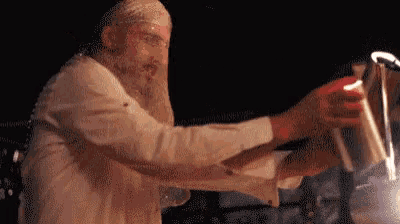 a man with a beard is making a drink with a shaker .