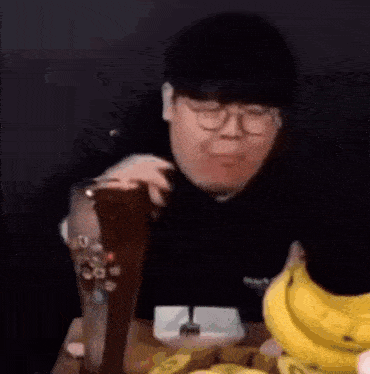 a man is sitting at a table eating bananas and drinking a beer .