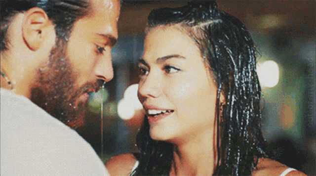 a man with a beard and a woman with wet hair are looking at each other