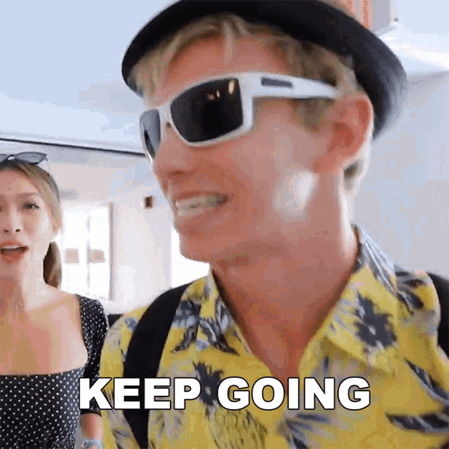 a man wearing a hat and sunglasses says keep going
