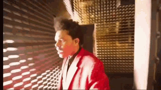 a man in a red jacket is walking through a dark room .