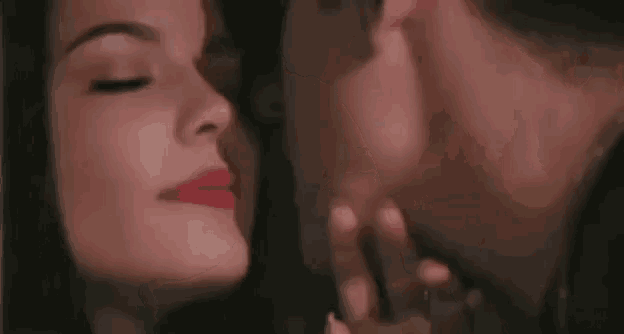 a man is kissing a woman on the cheek in a close up of their faces .