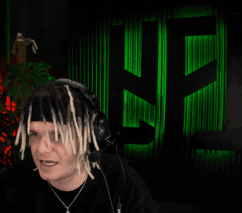 a man with dreadlocks is wearing headphones in front of a green sign that says nf