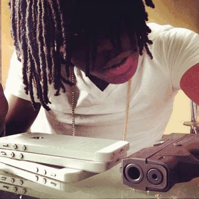 a man with dreadlocks sits next to a stack of cell phones