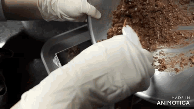 a person wearing gloves is pouring chocolate into a pan that says made in animatica on the bottom