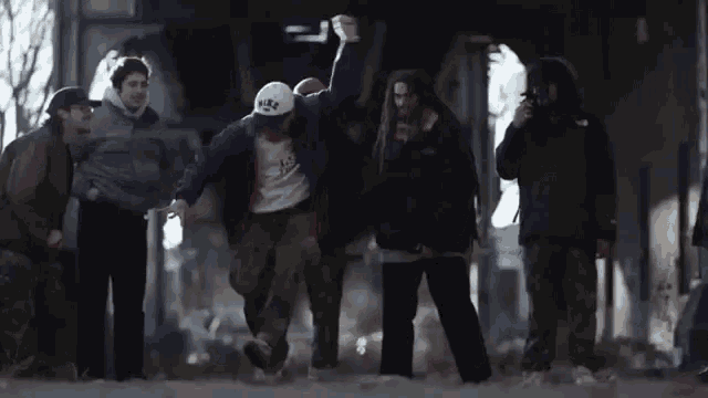a group of people are standing around a man wearing a white hat that says ice