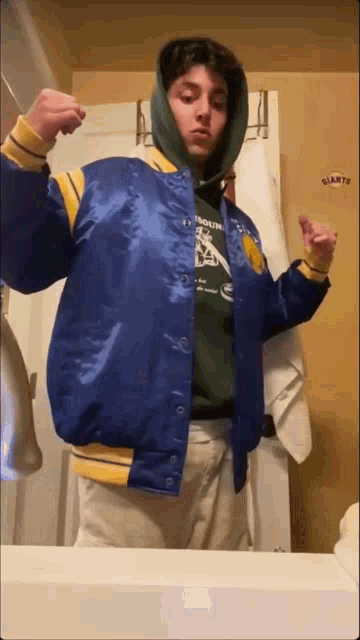 a man in a blue and yellow jacket is standing in front of a bathroom mirror