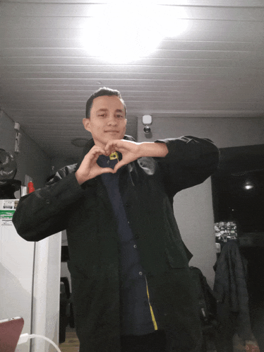 a man making a heart shape with his hands in a room
