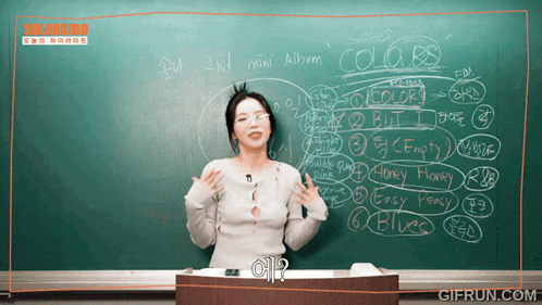 a woman stands in front of a blackboard that says colors on it