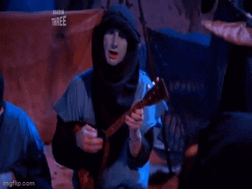 a man in a hood is playing a guitar in front of a crowd .